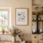 Puffin botanical wall art displayed in a bright cottage-style kitchen with warm neutral walls and natural wood accents.