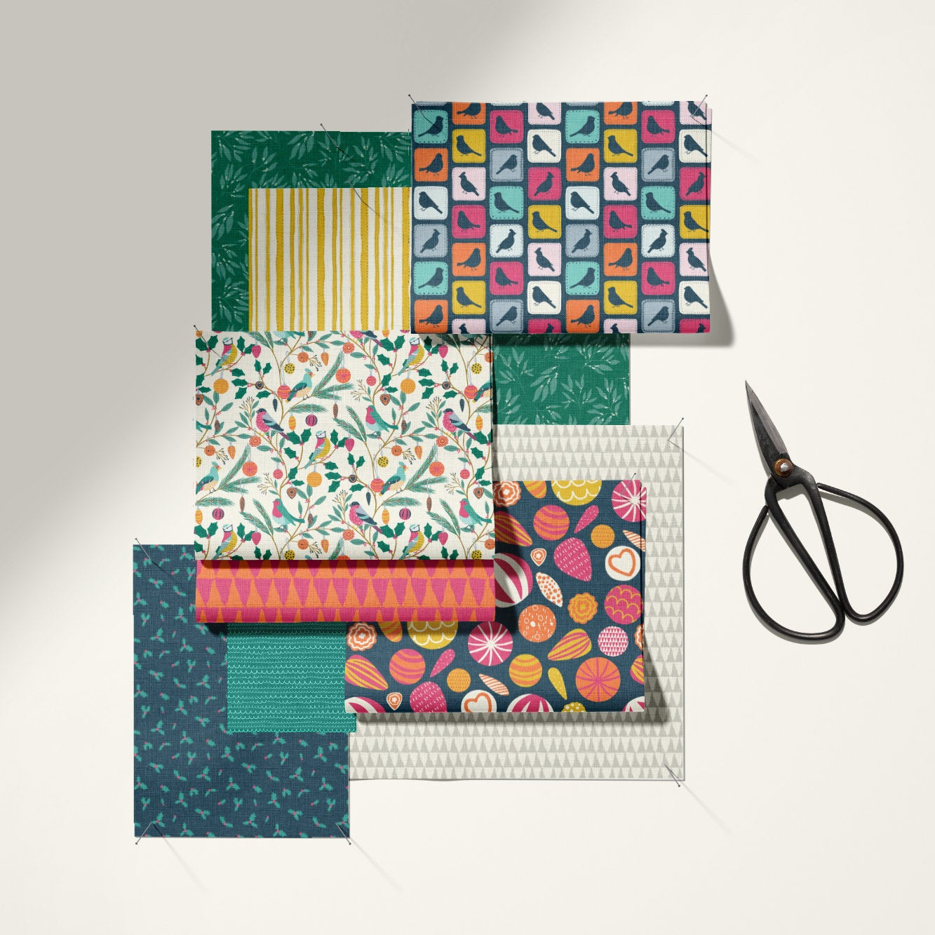A set of patterned paper sheets in assorted colors and designs, arranged next to a pair of black-handled scissors on a light beige background with soft shadows.