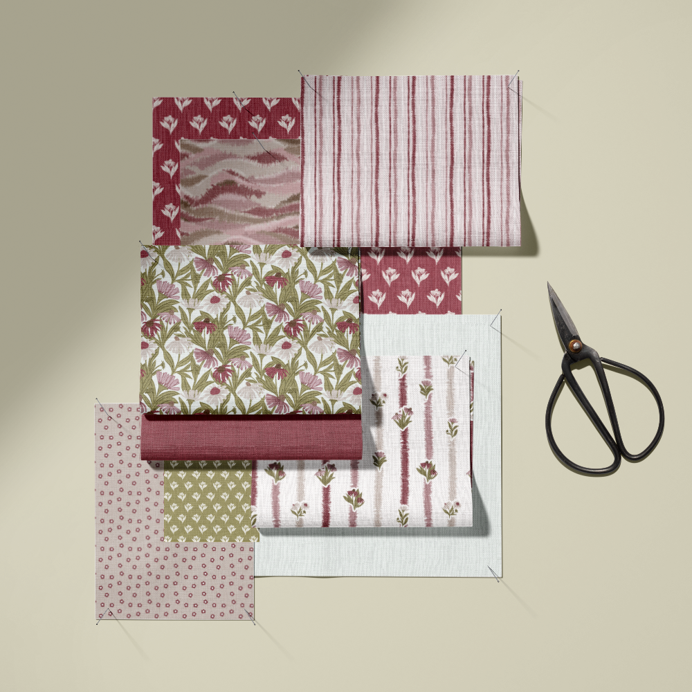 A set of patterned fabric swatches in shades of pink, red, green, and white, arranged neatly next to a pair of black-handled scissors on a warm beige background.