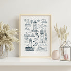 Lighthouse coastal art print with hand-drawn seaside illustrations displayed in a light wood frame with soft neutral styling.