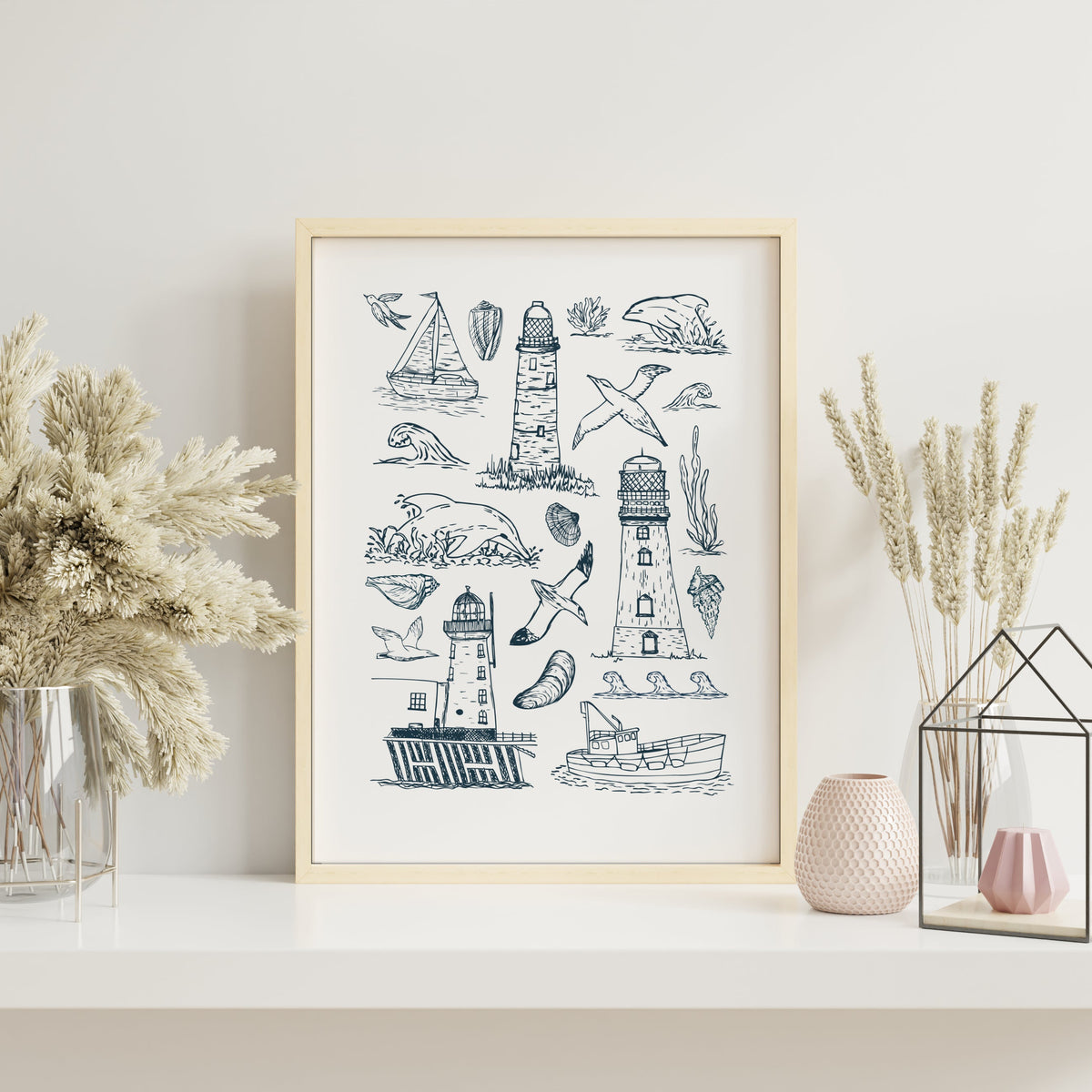 Lighthouse coastal art print with hand-drawn seaside illustrations displayed in a light wood frame with soft neutral styling.