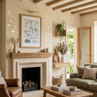 Lighthouse wall art displayed above a fireplace in a bright living room with exposed wooden beams and natural decor.