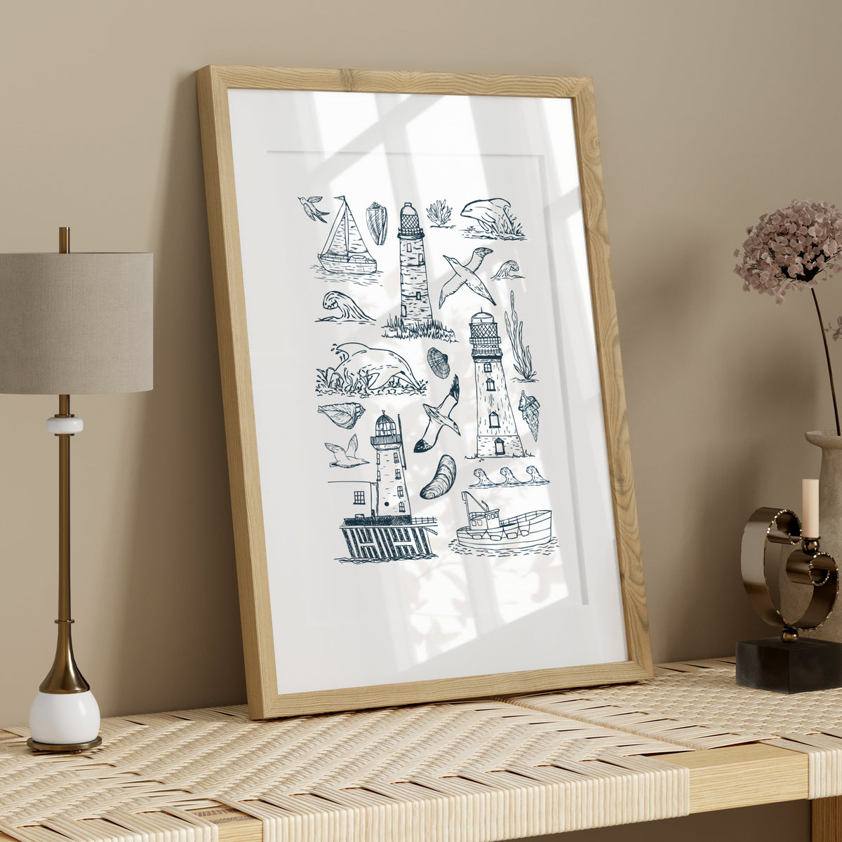 Hand-drawn nautical art print in a light wood frame styled on a neutral shelf with simple coastal-inspired accessories.