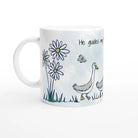 A white ceramic mug featuring a printed illustration of two white and gray geese walking in a field, accompanied by daisies, a butterfly, and the text 'He guides my.