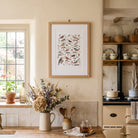 Garden birds botanical print displayed in a bright cottage-style kitchen with warm wood and soft neutral tones.
