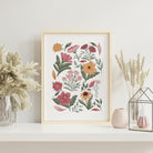 Botanical floral art print with hand-illustrated pastel garden flowers displayed in a light wood frame with soft neutral styling.