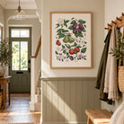 Hand-illustrated fruit and botanical print displayed in a warm neutral hallway with wood panelling.