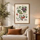 Christian fruit and botanical print displayed above a neutral sofa in a cosy living room with warm earthy decor.