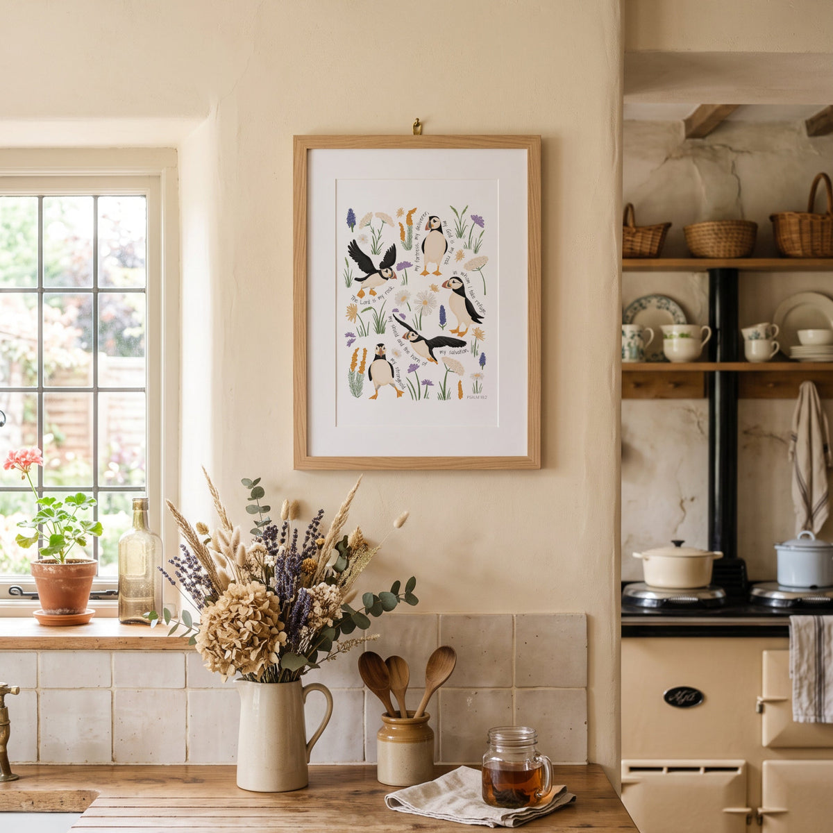 Hand-drawn puffin scripture print with sea holly displayed in a light cottage-style kitchen with soft neutral decor.